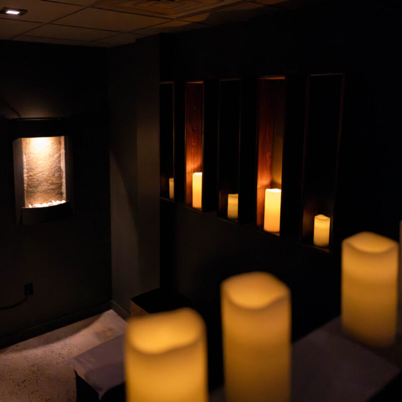 Dark massage room with soothing candles calming the space.